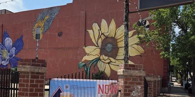 Colorful mural of flowers on a building with a "Now Open" banner and Presley’s sign.
