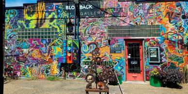 Colorful graffiti covers the exterior of Blo Back Gallery with a metal sculpture in front.