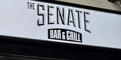 Sign for The Senate Bar & Grill with bold black and white lettering.