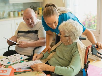 Caregiver assists elderly individuals with activities and paperwork in a cozy home setting.