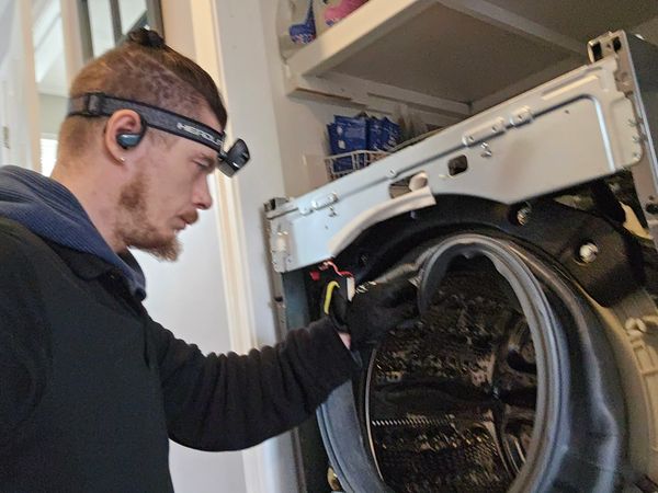 Man inspecting the inside of a washing machine.