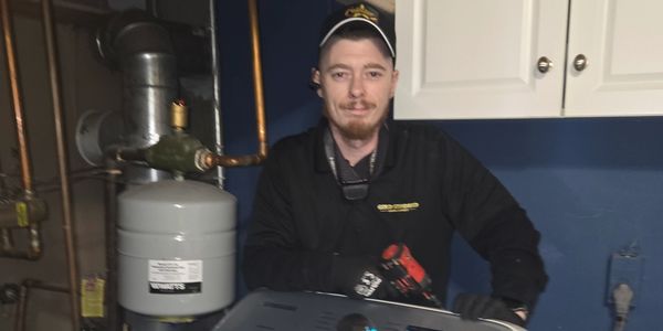 Technician posing with tools in a utility room.