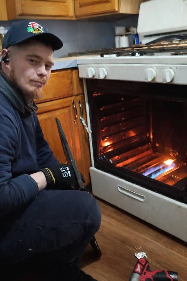 Man repairing a gas oven in a kitchen.