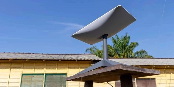 Modern satellite dish mounted on a wooden platform outdoors.