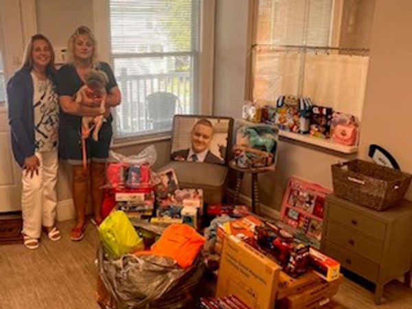 Two women with a kid, surrounded by toys and baby supplies.