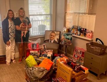 Two women with a kid, surrounded by toys and baby supplies.