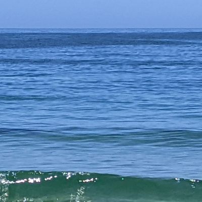 Calm ocean waves under a clear blue sky.