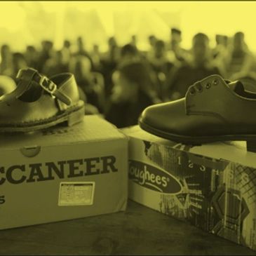 Pair of shoes displayed on boxes with people blurred in the background.