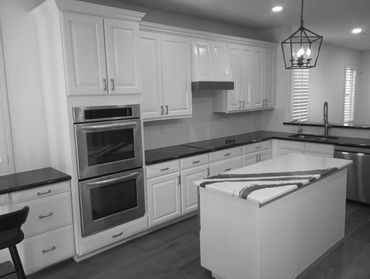 Modern kitchen with white cabinets and black countertops.