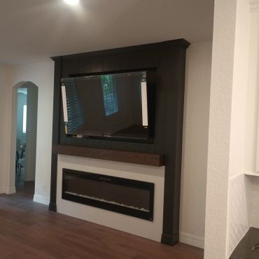 Modern living room with mounted TV and electric fireplace.
