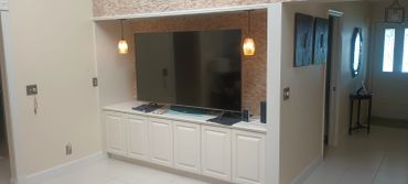 Modern TV nook with stone accent wall and warm pendant lights.