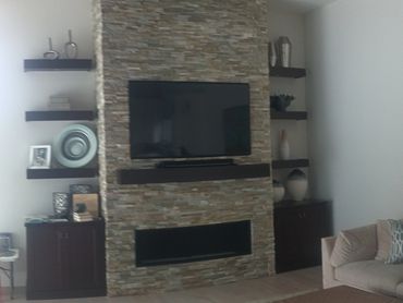 Modern living room with stone fireplace and mounted TV.