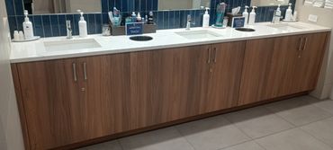 Modern bathroom sink area with three sinks and wooden cabinetry.