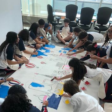 Children collaboratively painting a large mural indoors.