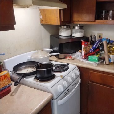 Kitchen before cleaning with dirty stove and countertops.