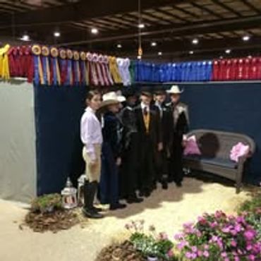 A group dressed in formal attire stands indoors with colorful ribbons above.