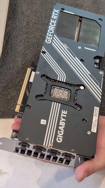 Hand holding a Gigabyte GeForce RTX graphics card on a foam pad.