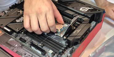 Hand installing an AMD Ryzen CPU onto a motherboard socket.