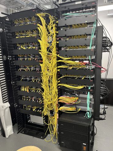 Network server racks with numerous yellow and colored cables connected.
