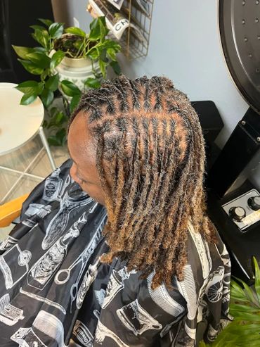 Freshly done short dreadlocks on a person sitting in a salon chair.