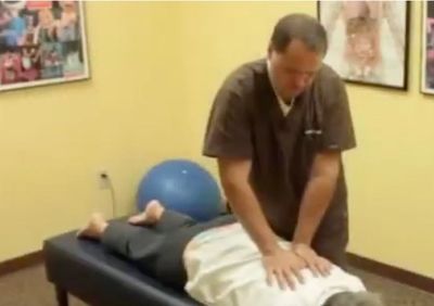 A chiropractor performing a back adjustment on a patient lying face down.