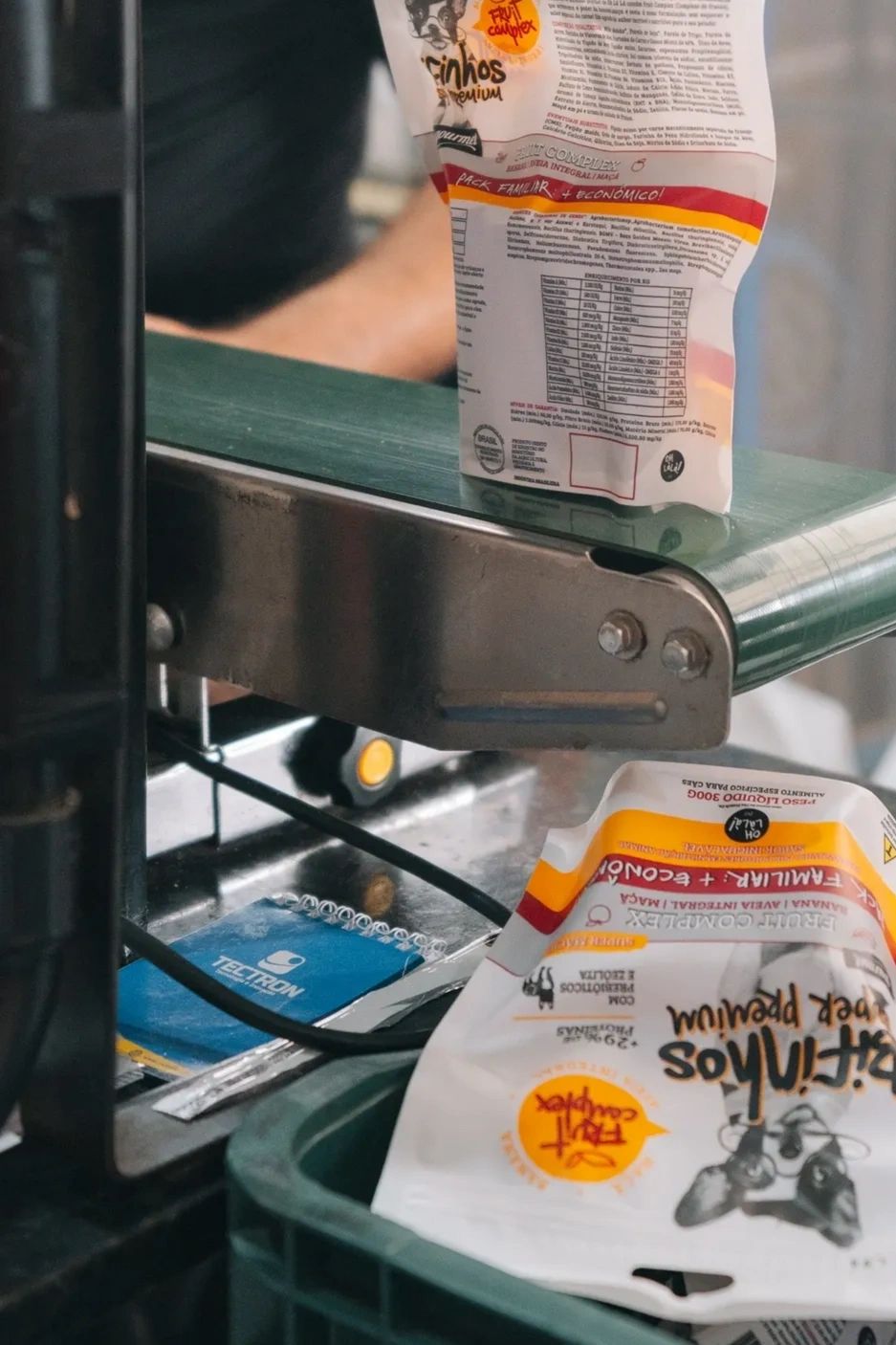 Packaging machine sealing bags of pet food on a conveyor belt.