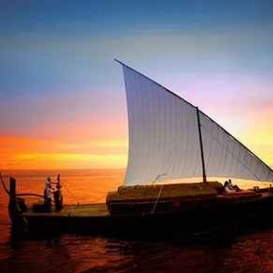 Traditional sailboat on calm water during sunset.