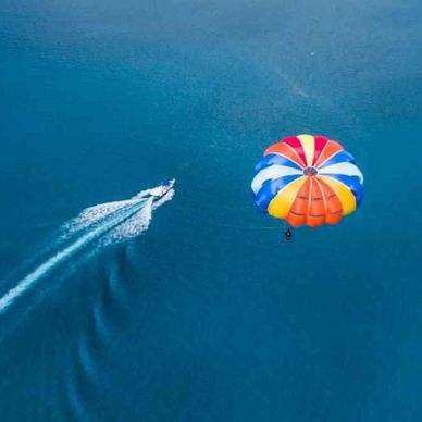 Parasailing over clear blue water with a speedboat.