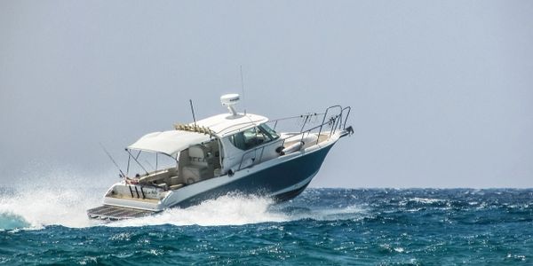 A motorboat speeding across choppy ocean waters under a clear sky.