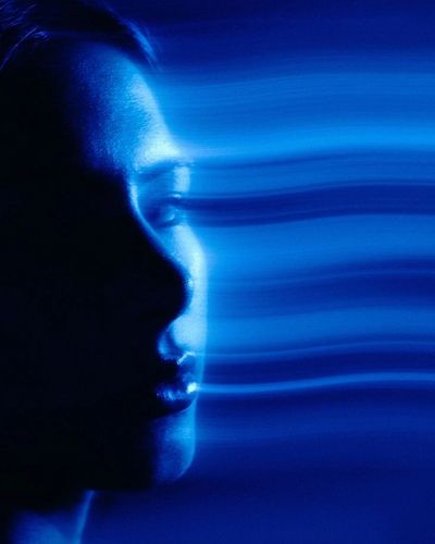 Profile of a face blending with blue light waves, creating a futuristic effect.