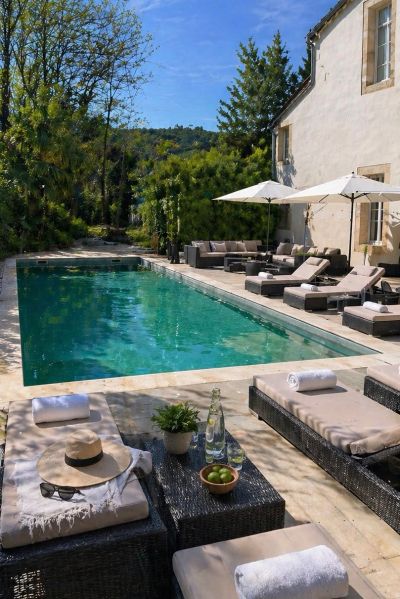 Elegant outdoor pool area with loungers, umbrellas, and scenic greenery.