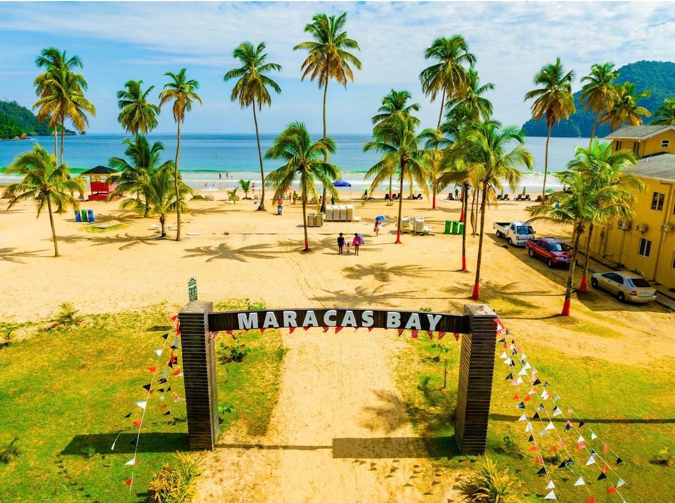 Entrance to Maracas Bay beach with palm trees and ocean view.