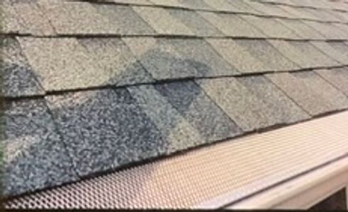 Roof shingles with a brick chimney and gutter guard.