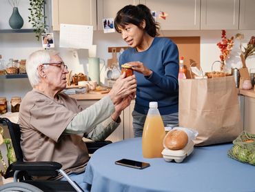 a man in a wheelchair and a woman assisting him by opening a jar.