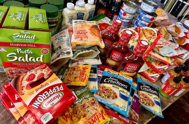 Various packaged food items including pasta salad, pepperoni, pizza sauce, and tuna creations.