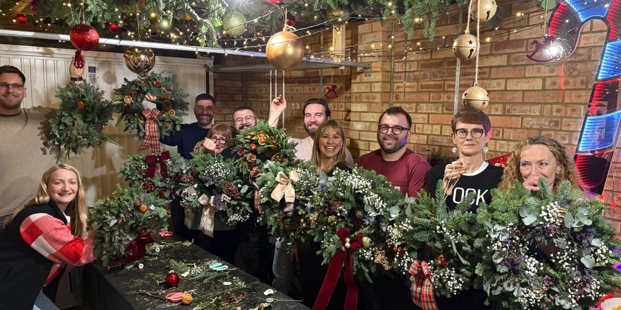 Group posing with Christmas wreaths in a festive setting.
