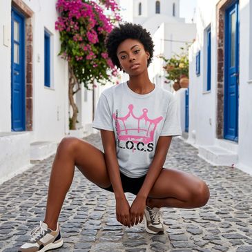 Woman squatting on a cobblestone street with white buildings and blue doors.