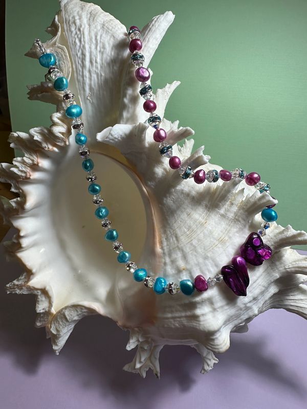 Colorful freshwater pearl and premium crystal necklace displayed on a large white seashell.