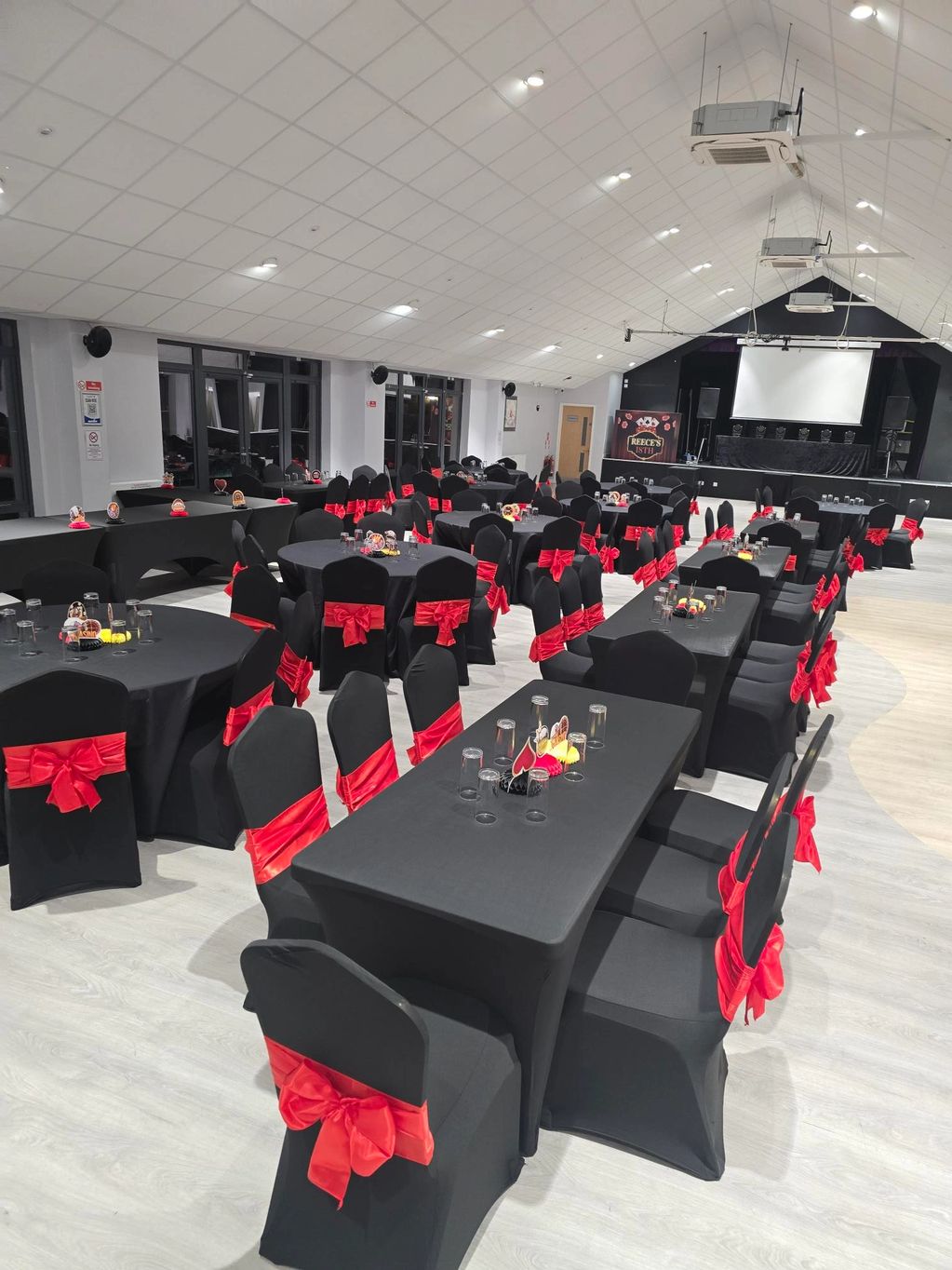 Event hall with black and red decorated tables and chairs.