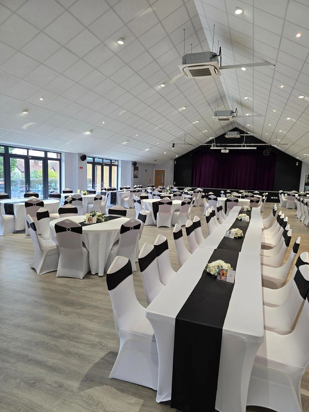 Elegant event hall with white and black decorated tables and chairs.