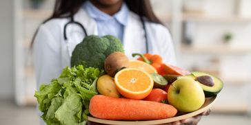 A doctor holding a plate of fresh fruits and vegetables.