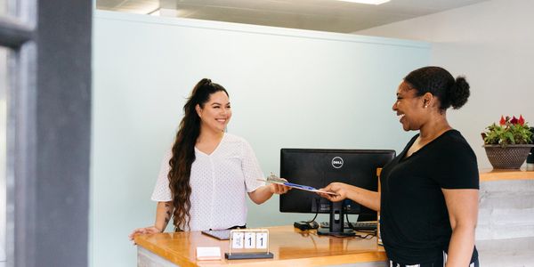 New chiropractor patient being greeted by the front desk assistant.
