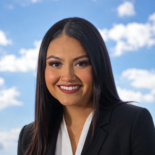 Professional woman smiling with blue sky background.