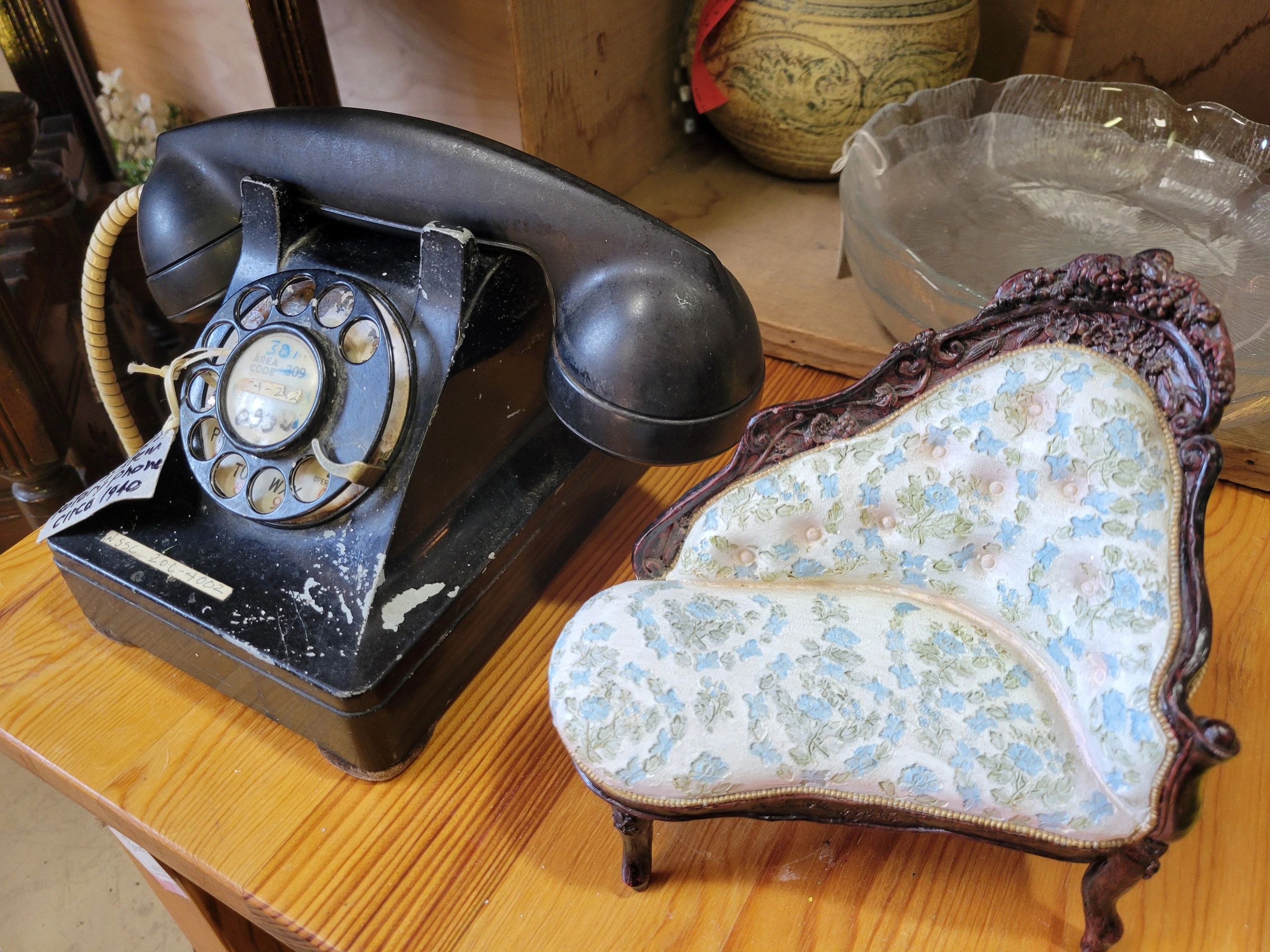 An antique rotary phone beside a miniature chair.
