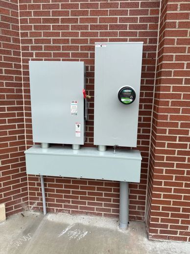 Two electrical panels mounted on a brick wall.