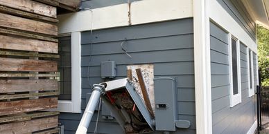 Damaged electrical panel on house exterior.