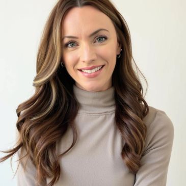 Smiling woman with long wavy hair and a beige turtleneck.