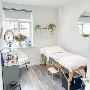 Bright and cozy beauty treatment room with a massage table and natural decor.
