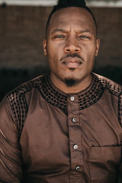 Close-up portrait of a serious man wearing a brown traditional shirt.