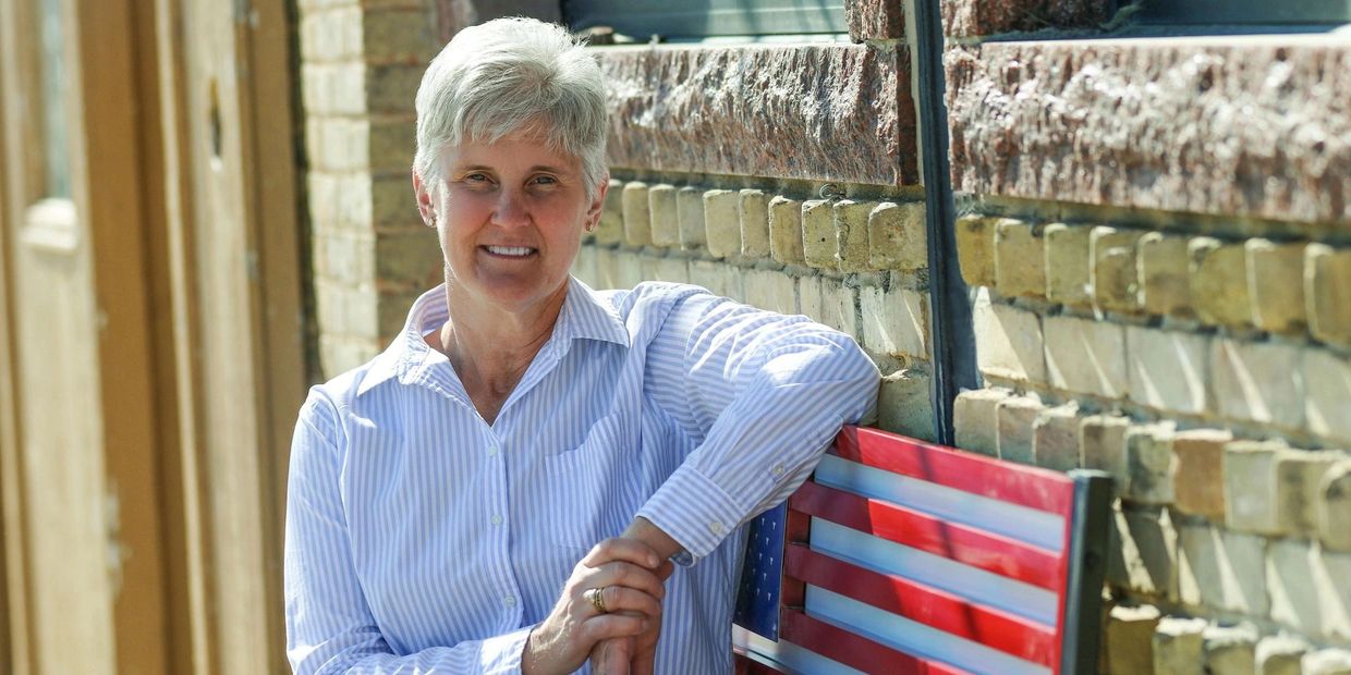 Woman leaning on a bench painted with the American flag, smiling.